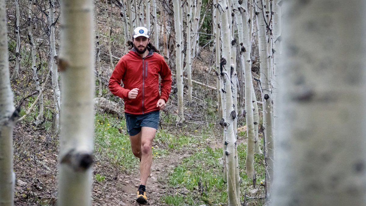 A trail runner moving through aspens in light mountain weather.